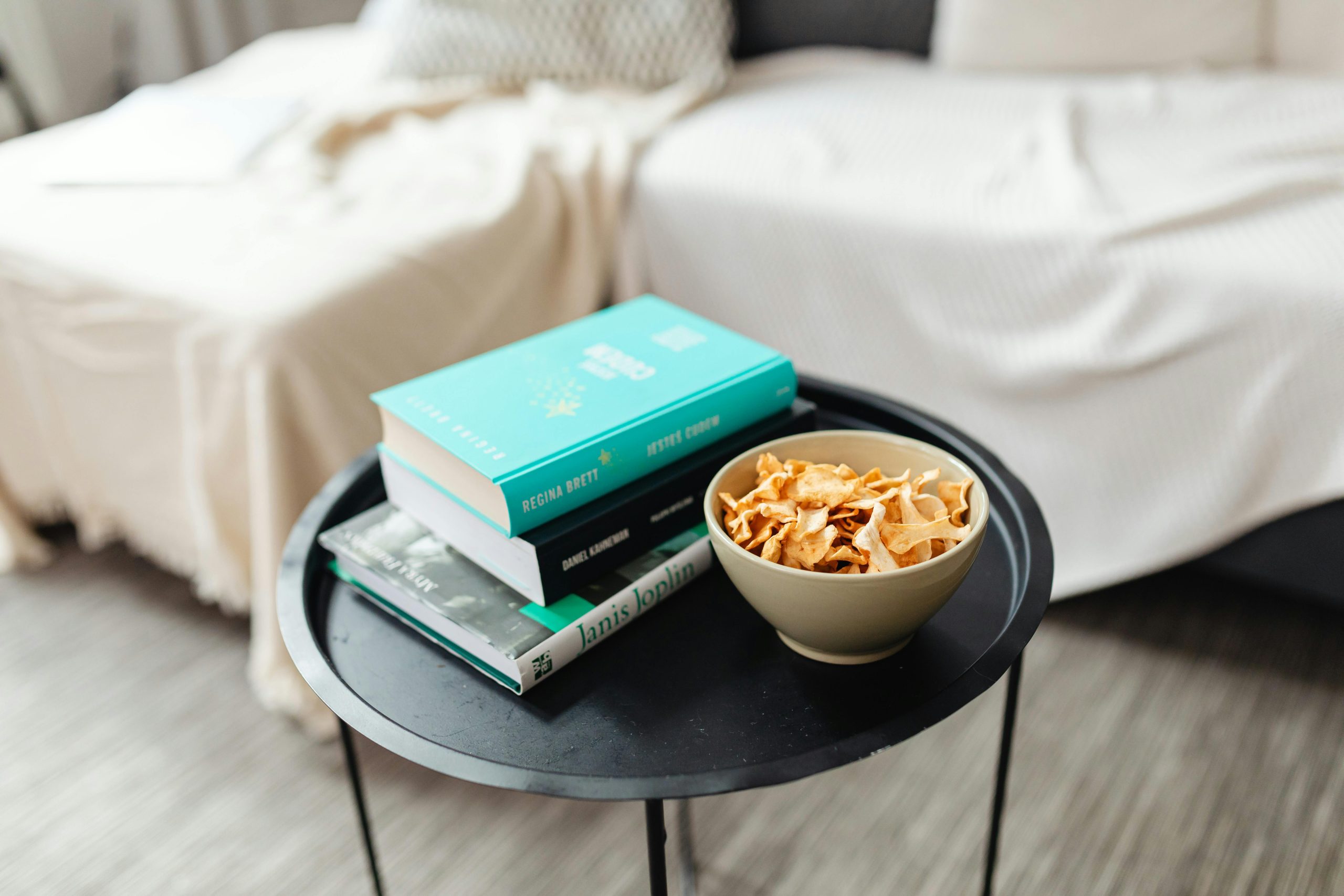 A cozy indoor setting with a stack of books and a bowl of snacks on a round table.